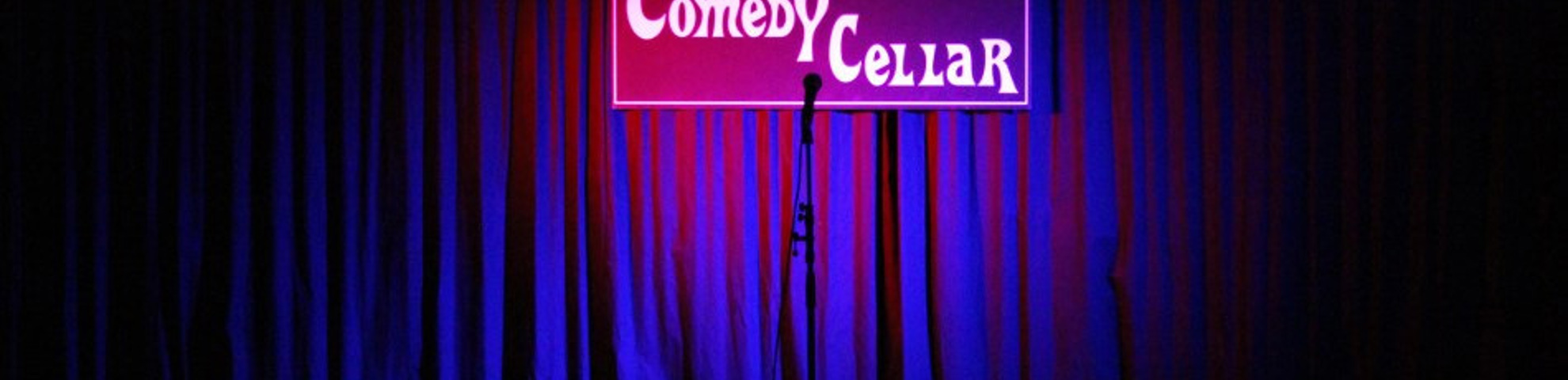 A curtain with a neon sign saying 'Comedy Cellar.'