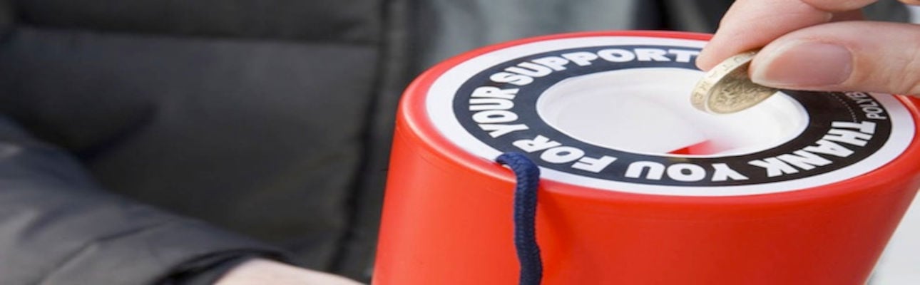 A person putting money in to a charity collection box. 