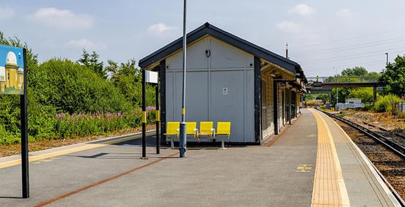 An outdoor seating area and station signage on the platform at Bidston station. 