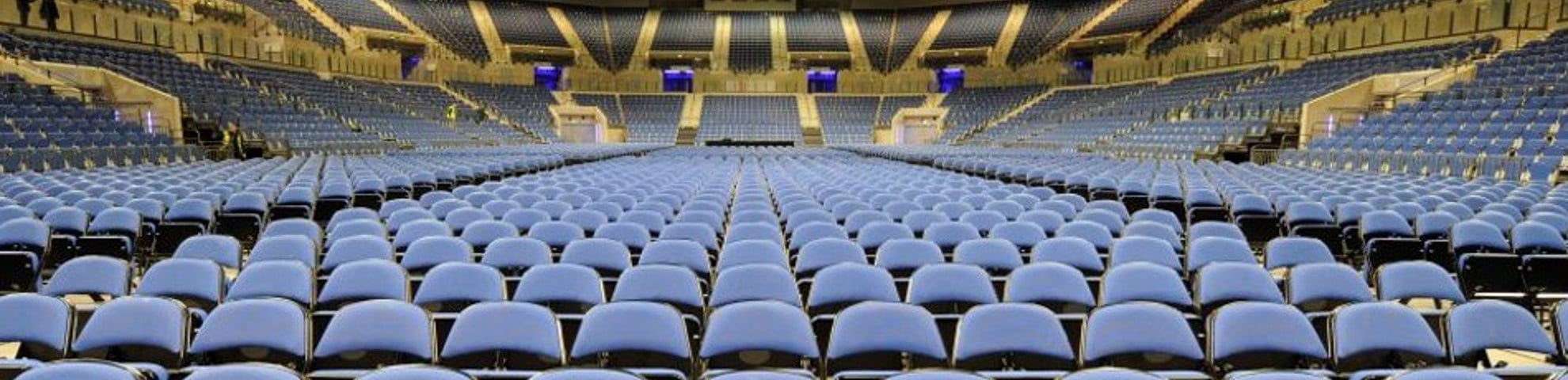 The interior of the arena. There is a number of blue seats. 