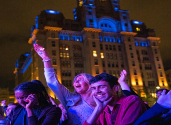 Young people enjoying a concert at night time at the pier head