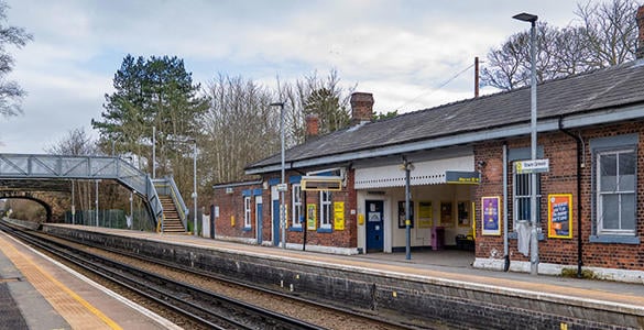 The platform at Town Green station. Station buildings and a pedestrian footbridge appear. 