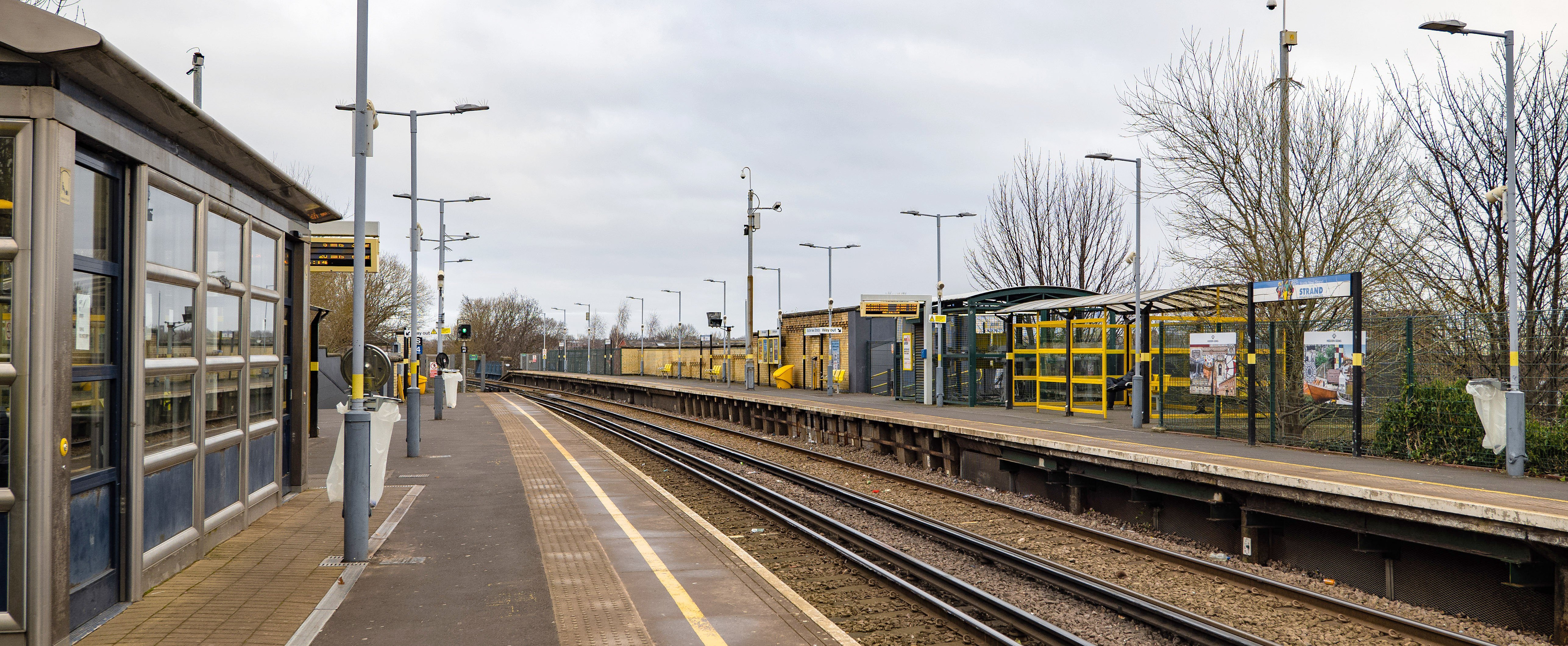 The platform at Bootle New Strand station. There are lampposts, sheltered seating and rubbish bins on the platform. 