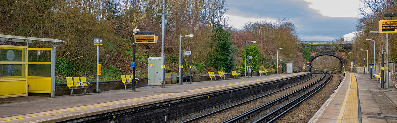 The platform at St Michaels station. Seating and digital signage appears along the platform. Trees and a tunnel bridge appear in the distance. 
