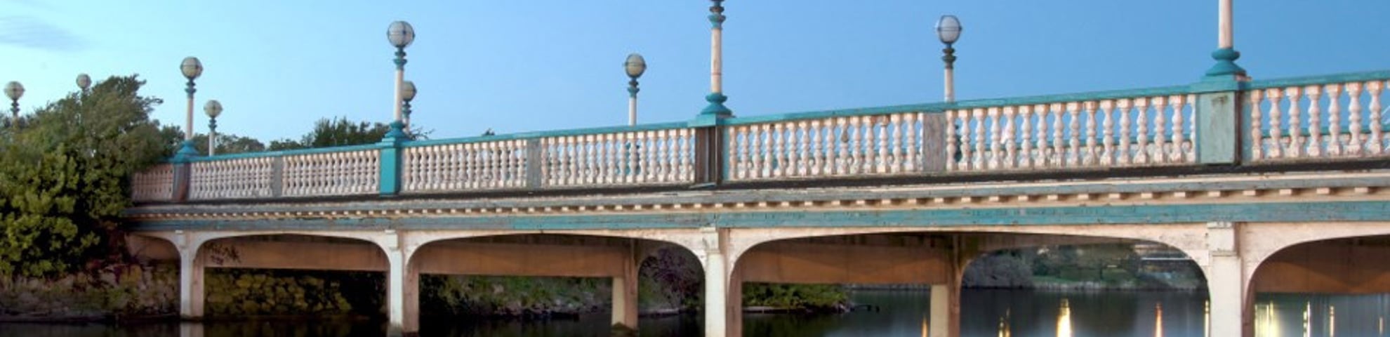 A large bridge over a lake. It is daytime and the sky is blue. 