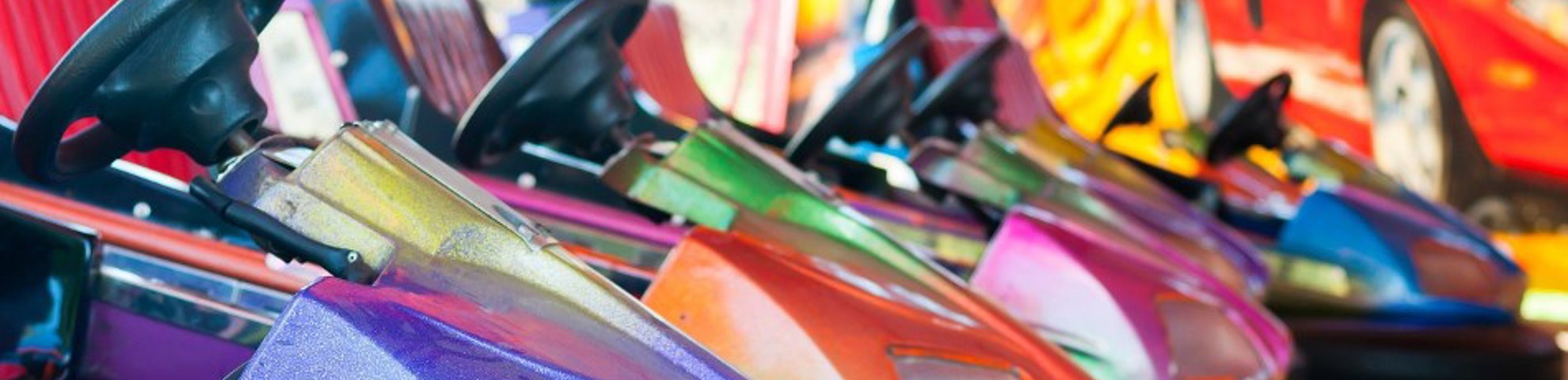 Several different brightly coloured bumper cars in a line.