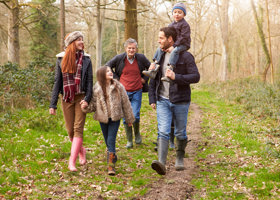A family of five walking through a wooded forest on a winters day. 