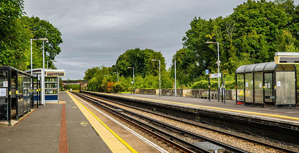 The platform at Spital station. Sheltered seating areas, digital information boards and trees appear. 