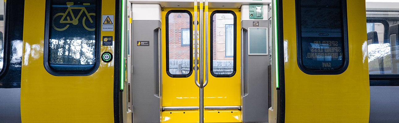 Open doors of a 777 train. The inside of the train and hand rails are shown. 