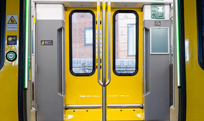 Open doors of a 777 train. The inside of the train and hand rails are shown. 