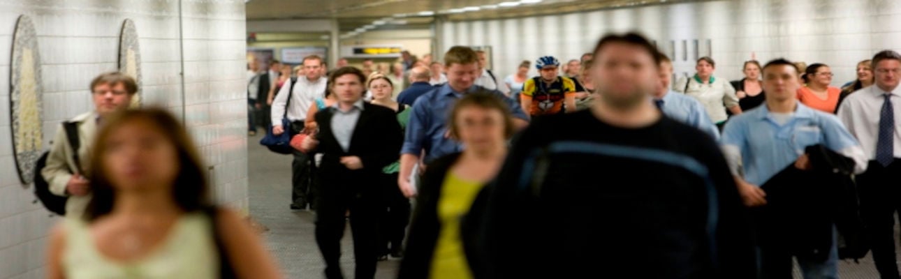 A crowd walking through a Merseyrail station.