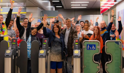 Members of the Merseyrail team stood behind ticket barriers at a Merseyrail station. 