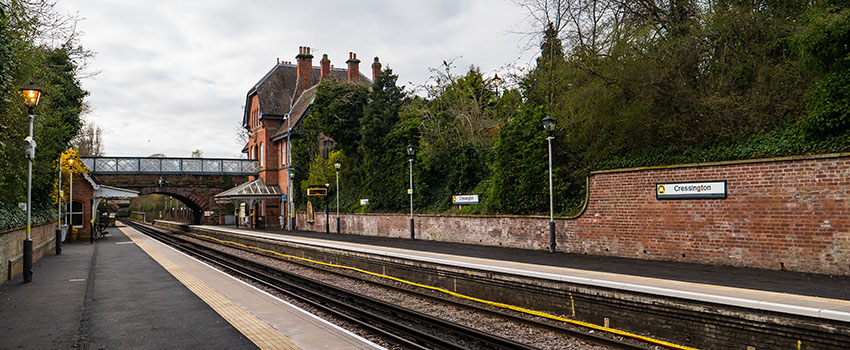 The platform at Cressington station. Station buildings and a tunnel bridge are in the distance. 