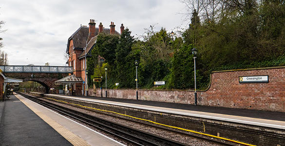 The platform at Cressington station. Station buildings and a tunnel bridge are in the distance. 