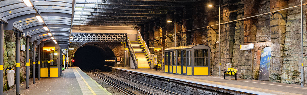 The underground station platform at Green Lane. Sheltered seating, signage and a pedestrian footbridge appears. 