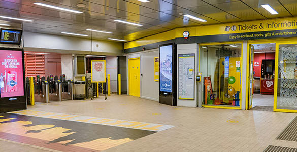 The ticket office and ticket gates at Liverpool Lime Street low level station. There is a tiled mural of Liverpool city centre sky line on the station floor.