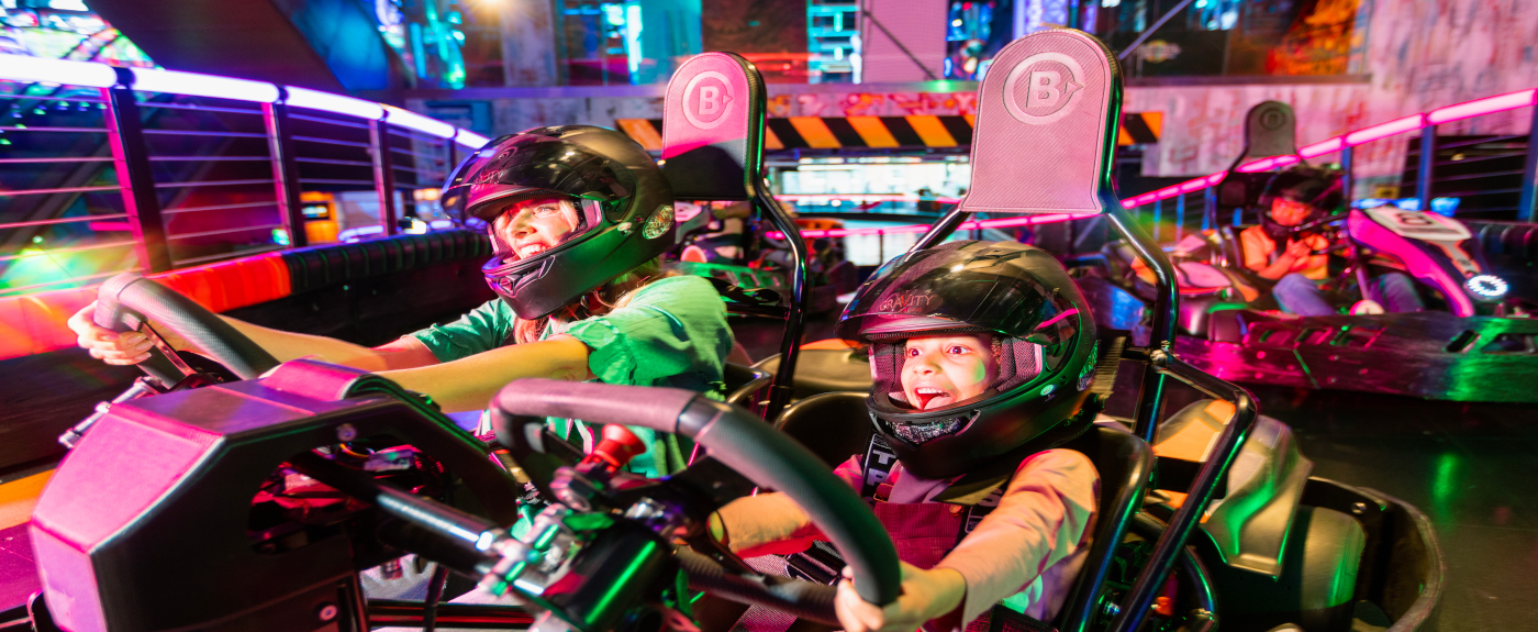 Two people wearing helmets driving a go kart.