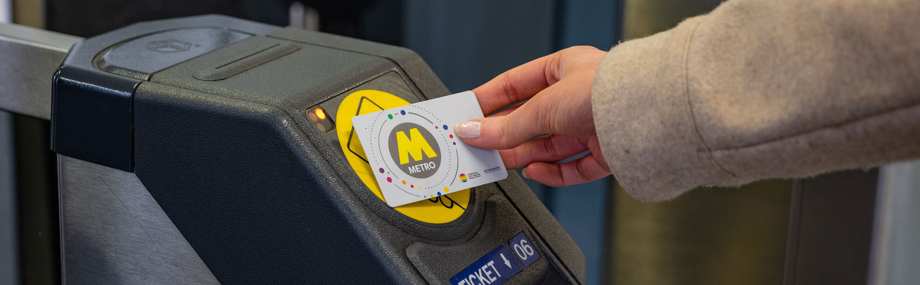 A passenger tapping a railpass card on a ticket barrier. 