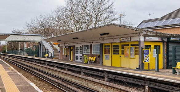 The platform at Manor Road station. There is a pedestrian footbridge, outdoor seating and a station building.