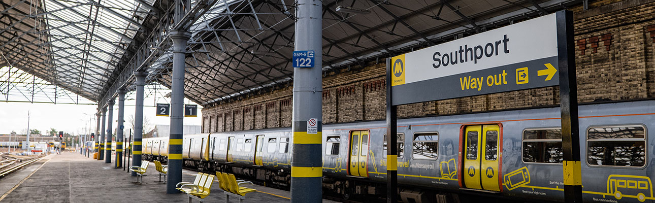 A train at the platform at Southport station. A sign stating the station name and directions for the way out appears. 