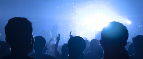 A crowd enjoying a concert with blue lighting.