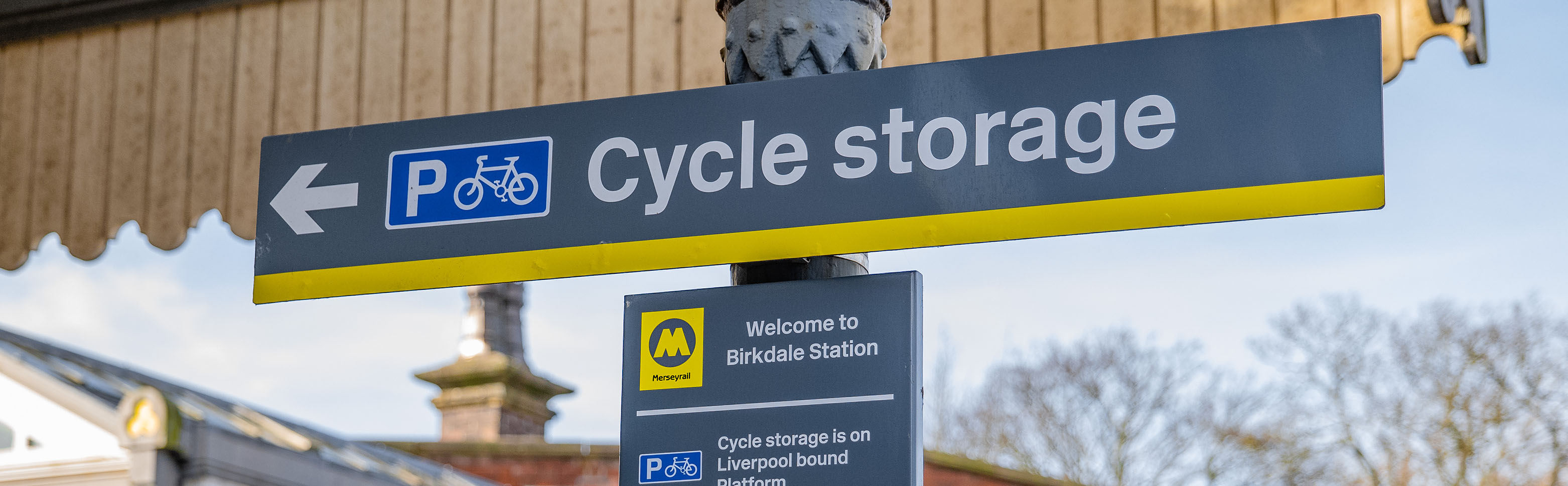 A sign fixed to a post shows directions for cycle storage at a station.  