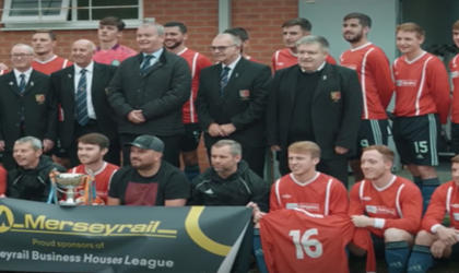 A football team holding a Merseyrail banner. 