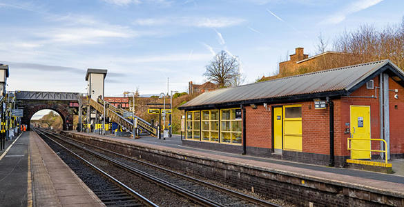 The platform at Hunts Cross station. A bridge, stairway and sheltered seating appears. 