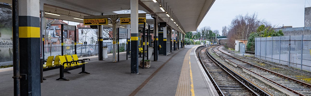 The platform overlooking railway tracks at West Kirby station. Shelter, seating and digital information boards appear. 