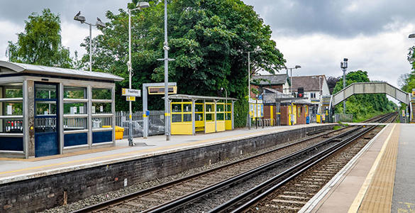 The platform at Freshfield station. Sheltered seating and signage appears. A pedestrian footbridge is in the distance. 
